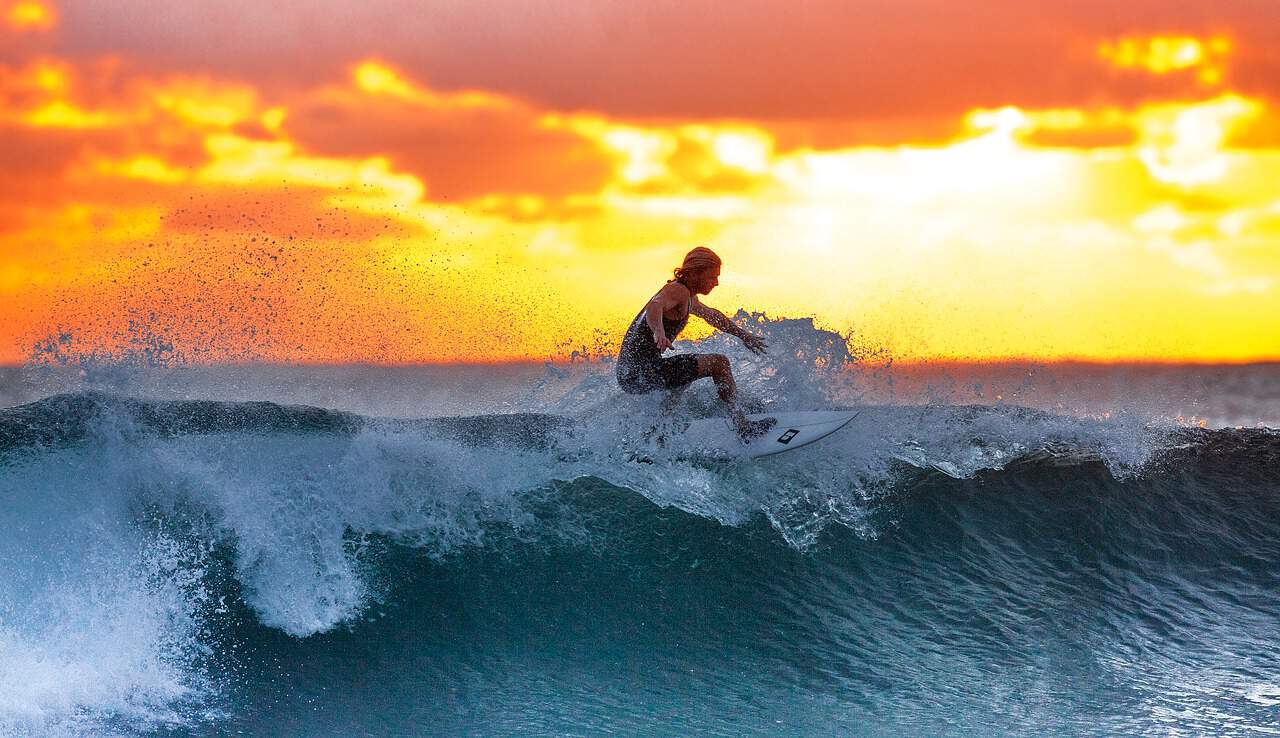 Surfer riding wave at sunset